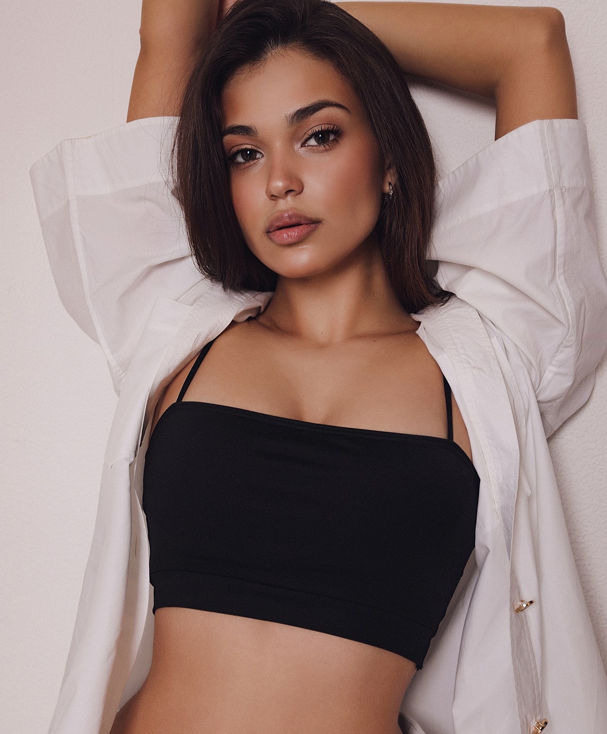 Charlotte, NC breast augmentation model posing in stylish black top and white shirt.
