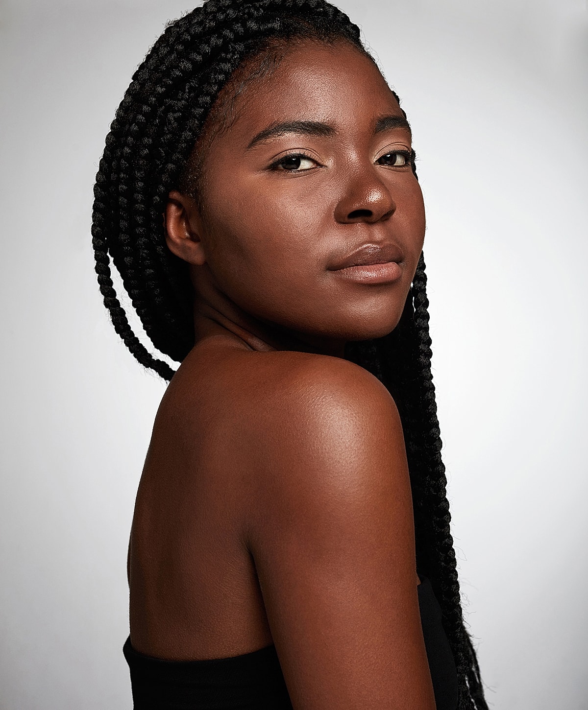 Charlotte, NC Rhinoplasty model with braids posing against a light background.