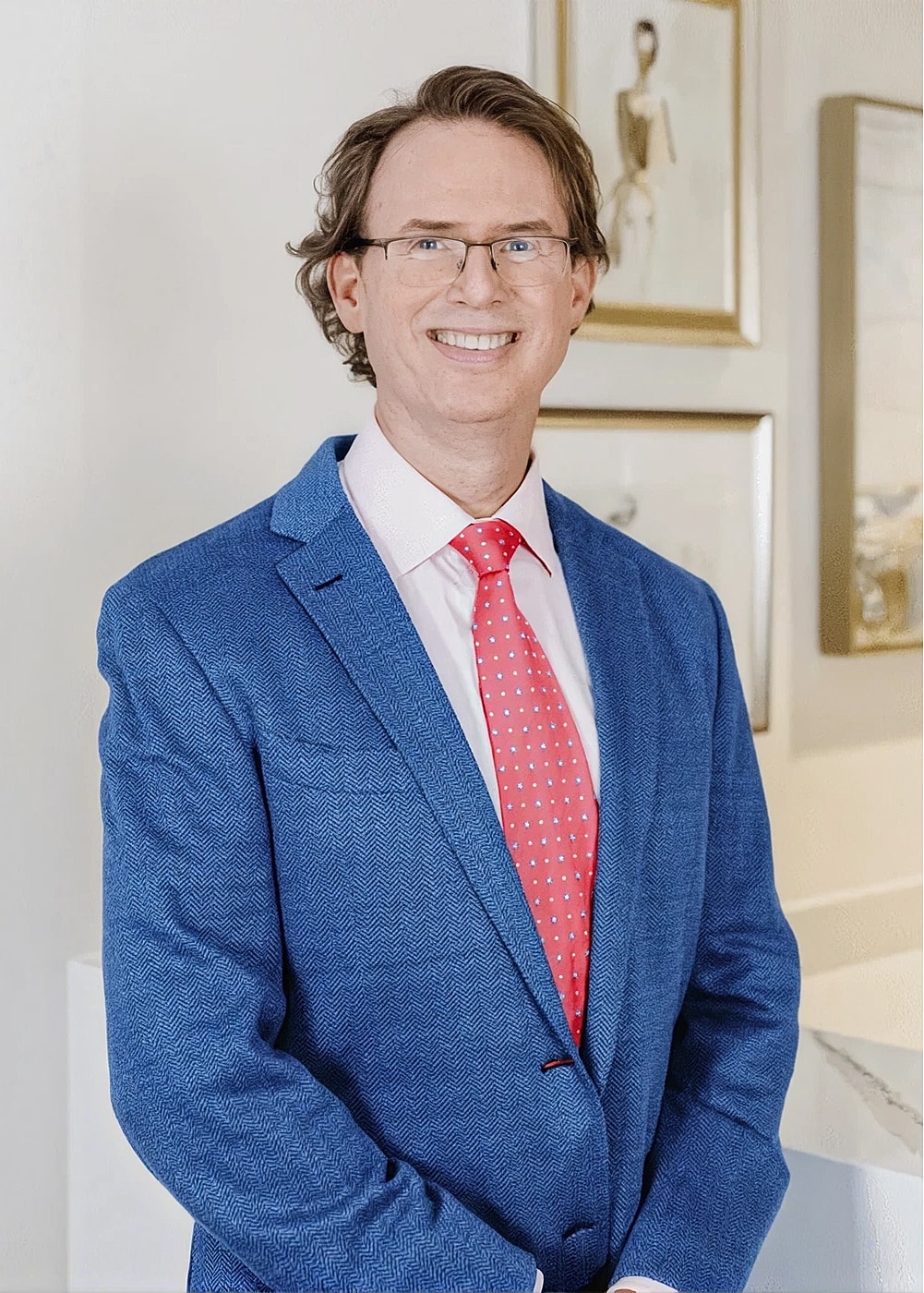 Man in blue suit and pink tie, smiling.