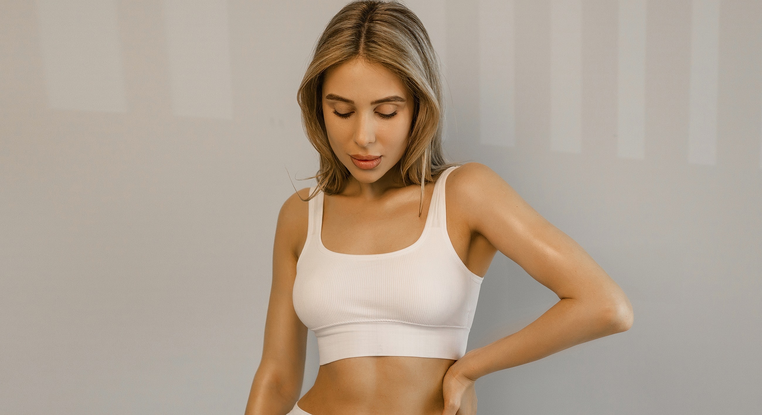 Woman in white crop top looking down.
