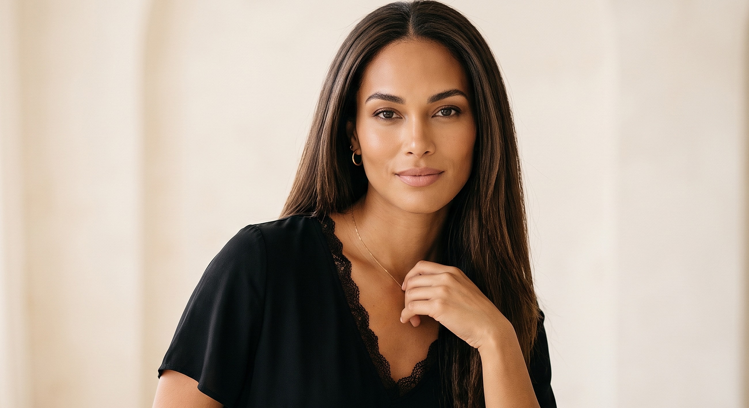 Woman in black top, posing against neutral background.